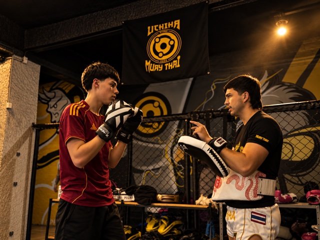 Aluno treinando socos com professor e manoplas