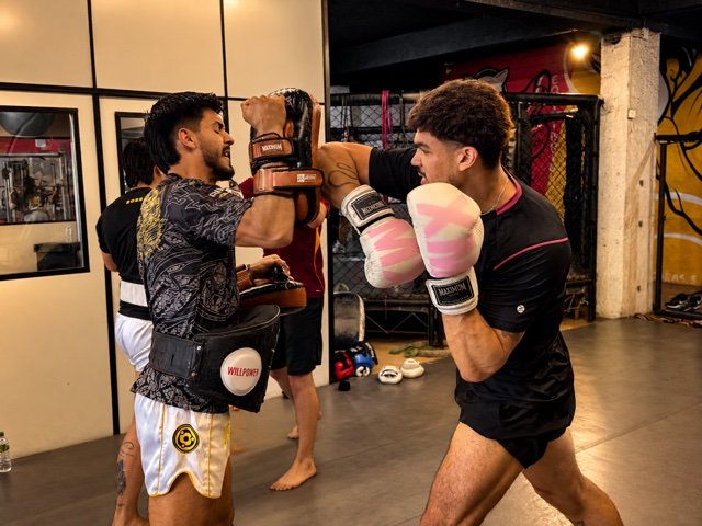 Alunos praticando boxe com luvas e manoplas